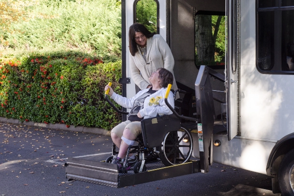 Patient in wheelchair using a lift to get onto a shuttle bus